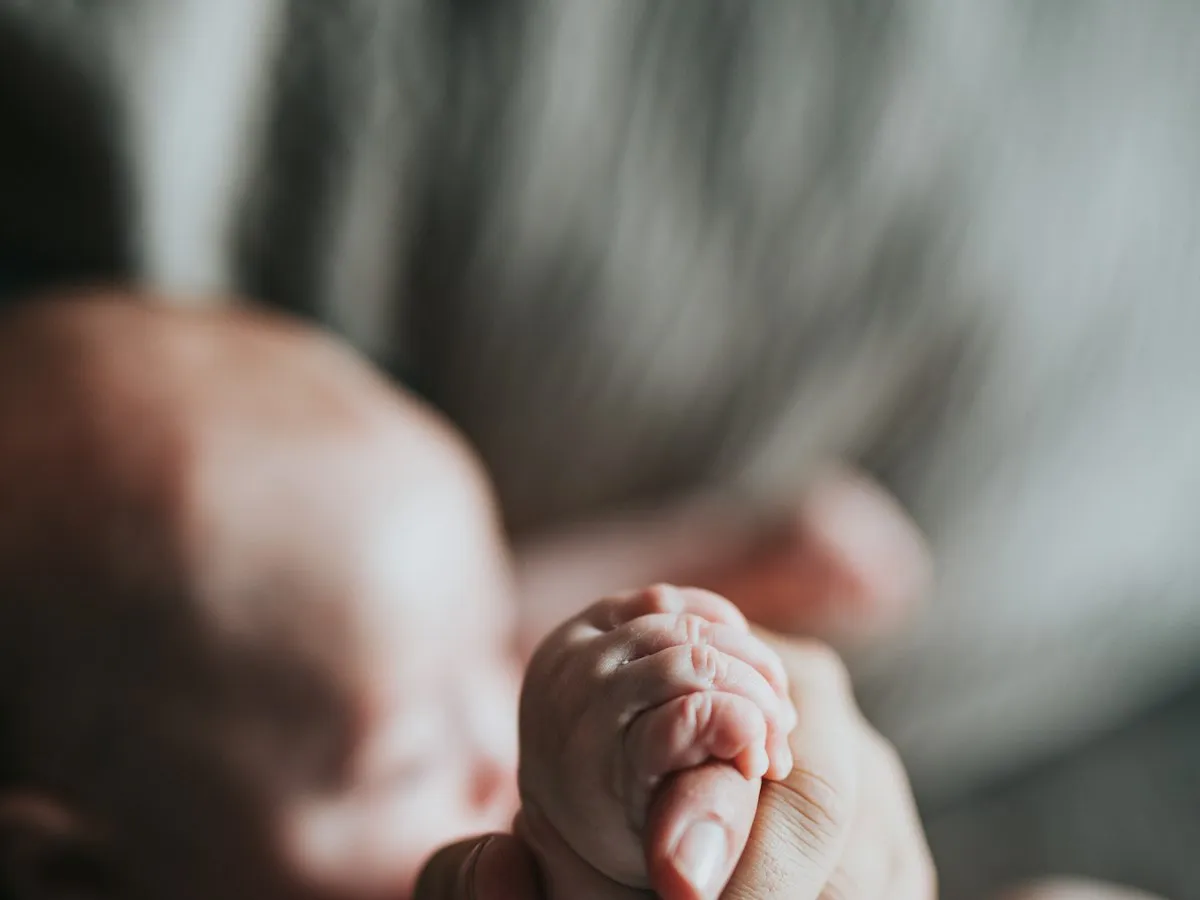 A tiny baby's hand resting in an adult's hand