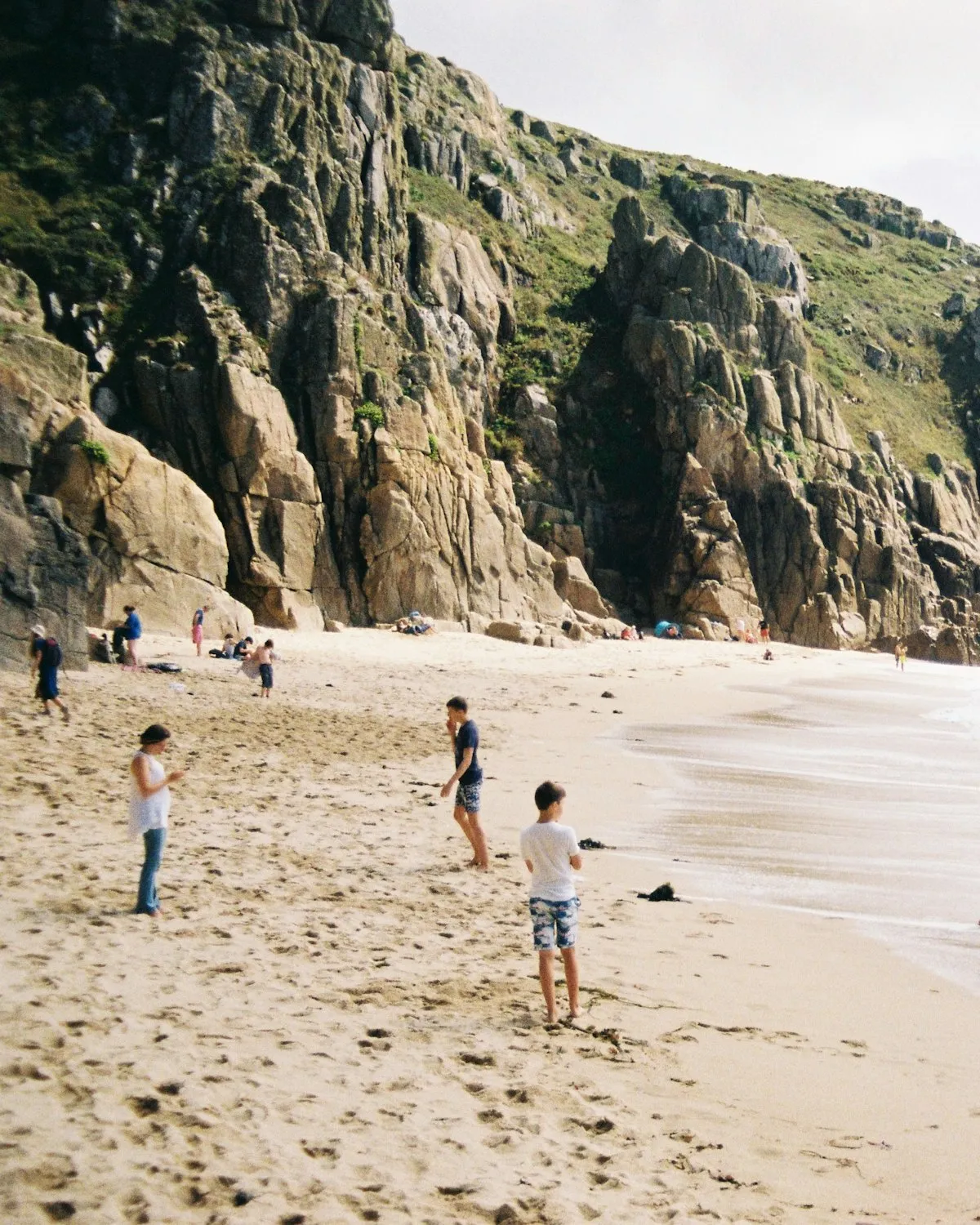 Families on a sandy Cornish beach between granite cliffs