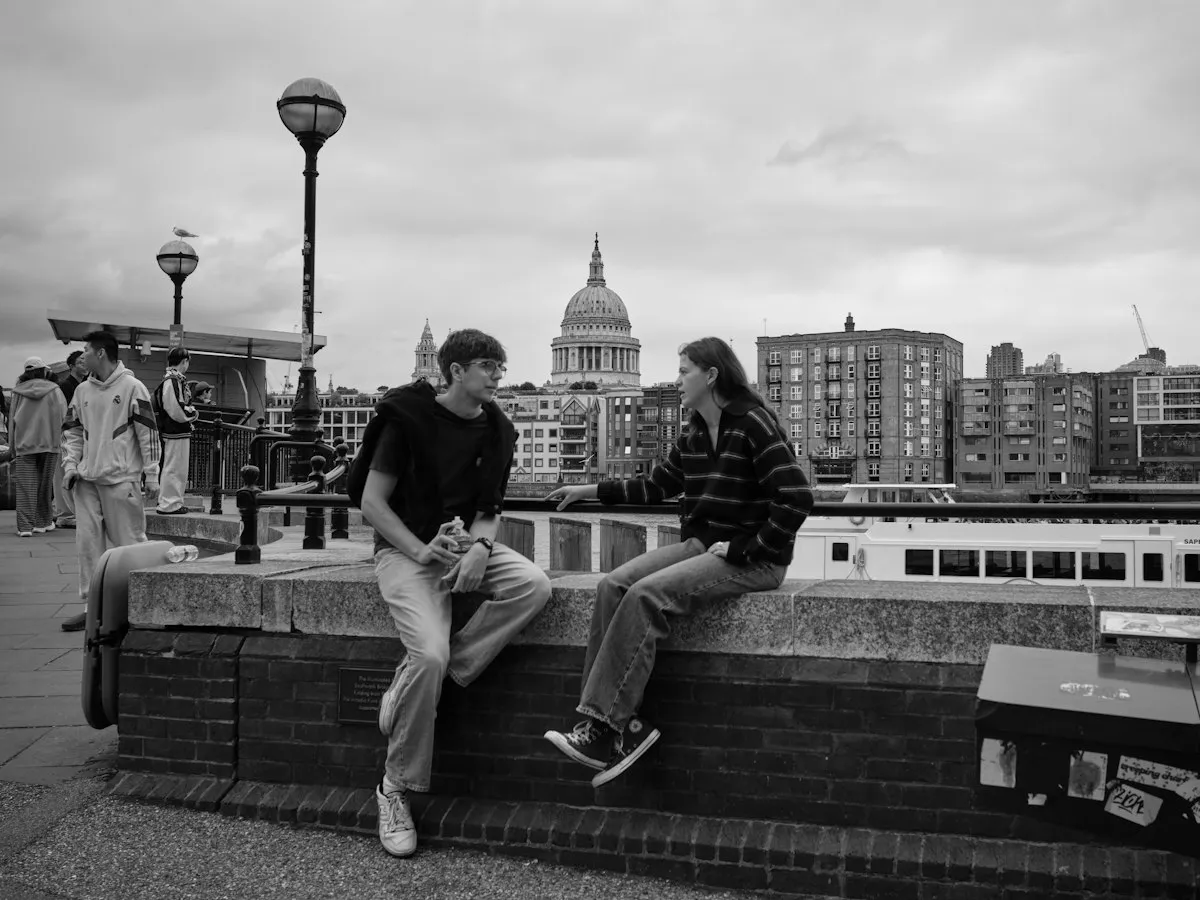 Two friends talking on a wall by the Thames, with St Paul's Cathedral behind them