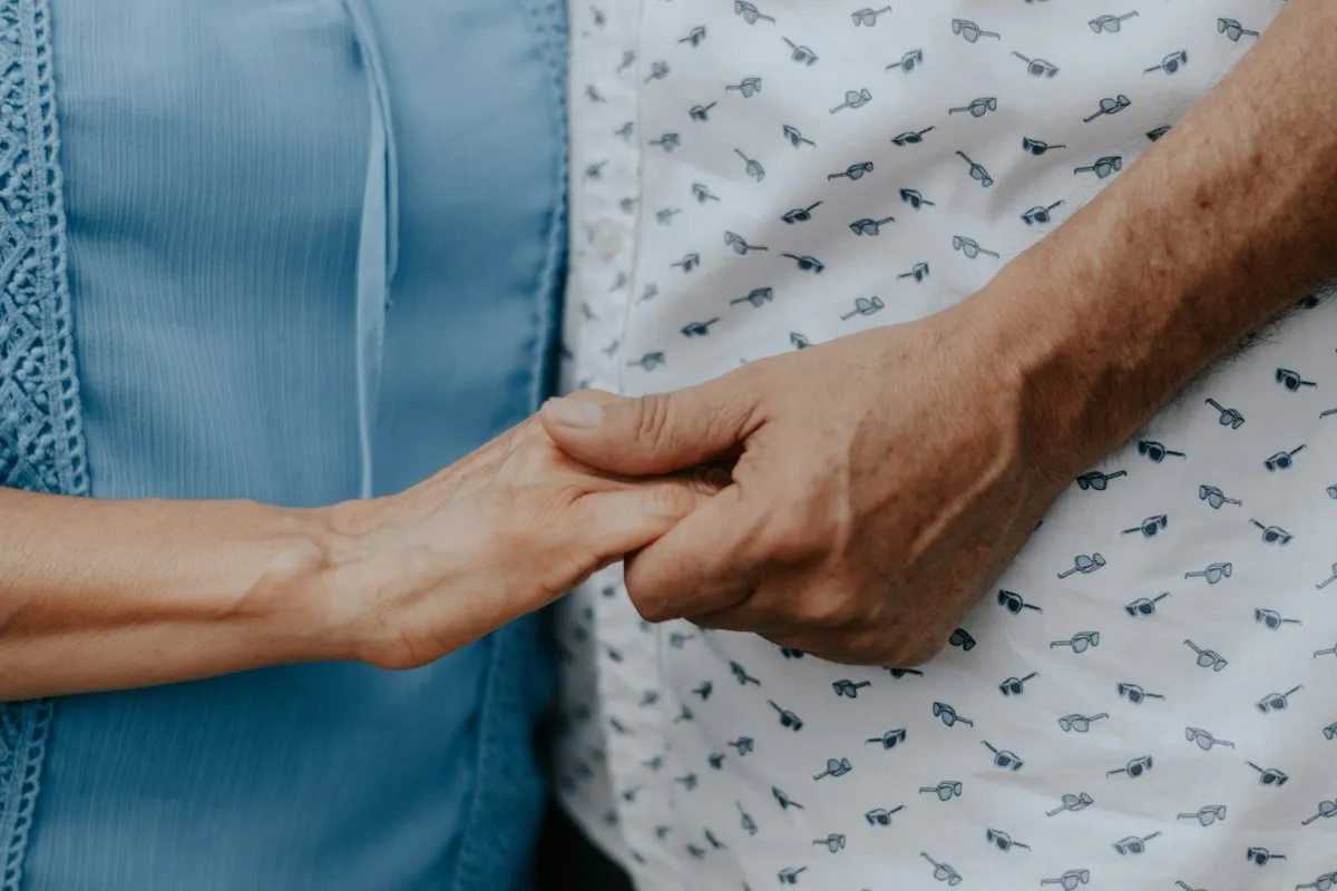 Two people holding hands in a quiet moment of support