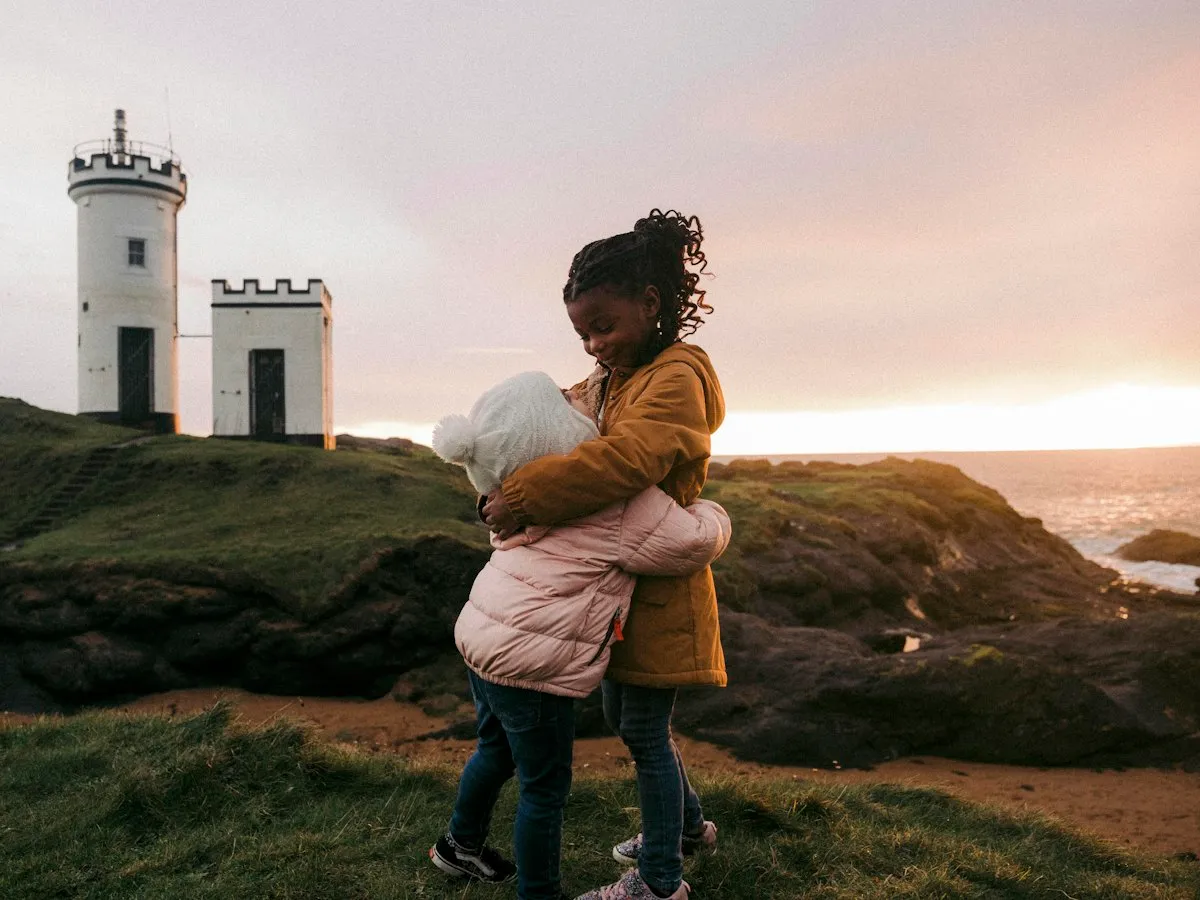 Two children hugging beside Elie Ness lighthouse in Fife at sunset