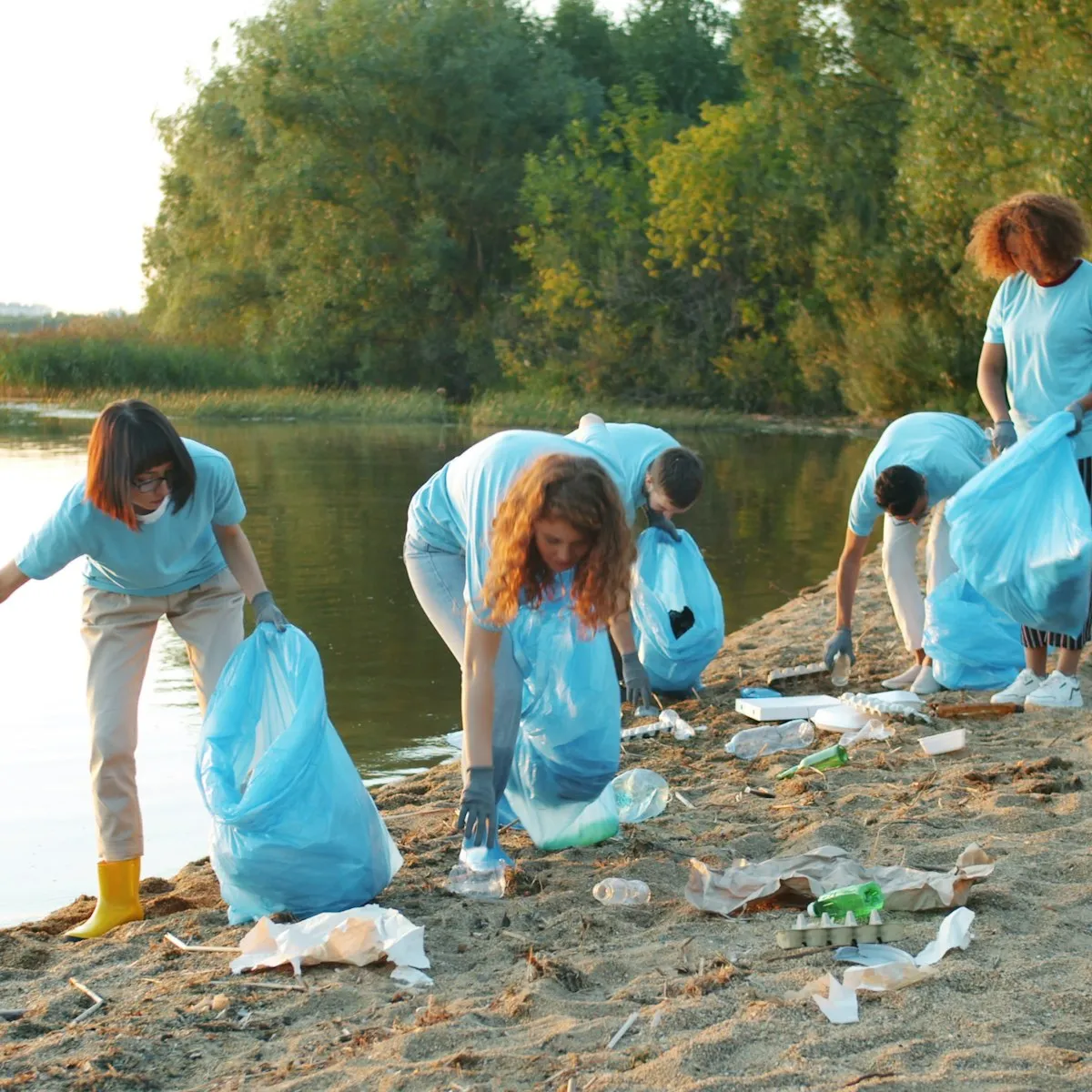 Volunteers in matching T-shirts collecting litter from a lakeside shore