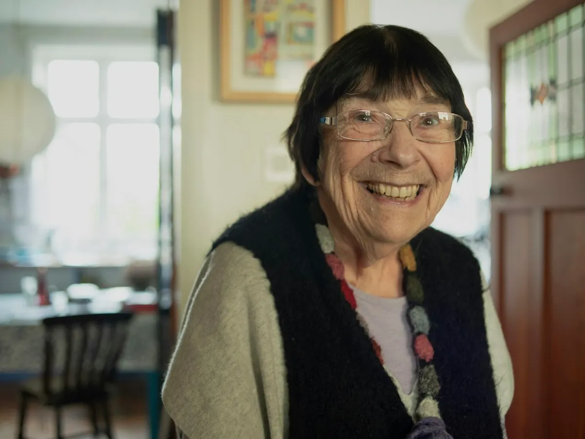 An older woman with glasses smiling warmly in her home