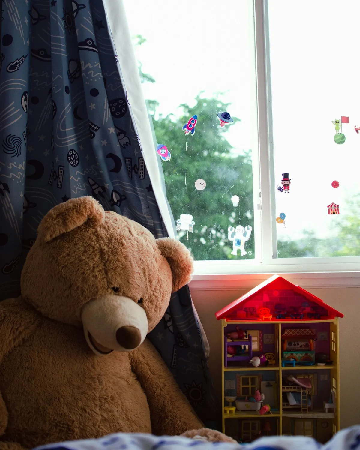 A big teddy bear sitting by a child's bedroom window