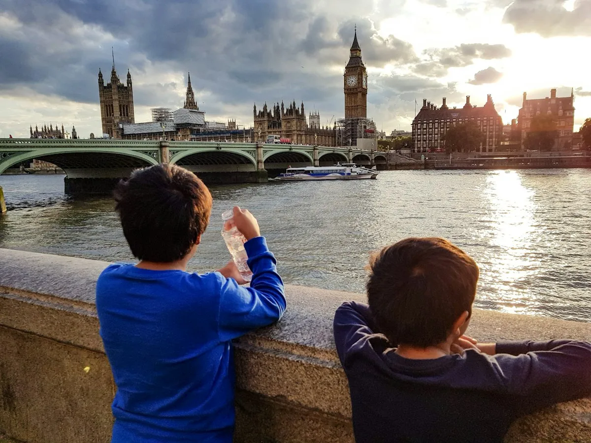 Two boys looking out across the Thames at Westminster and Big Ben at golden hour